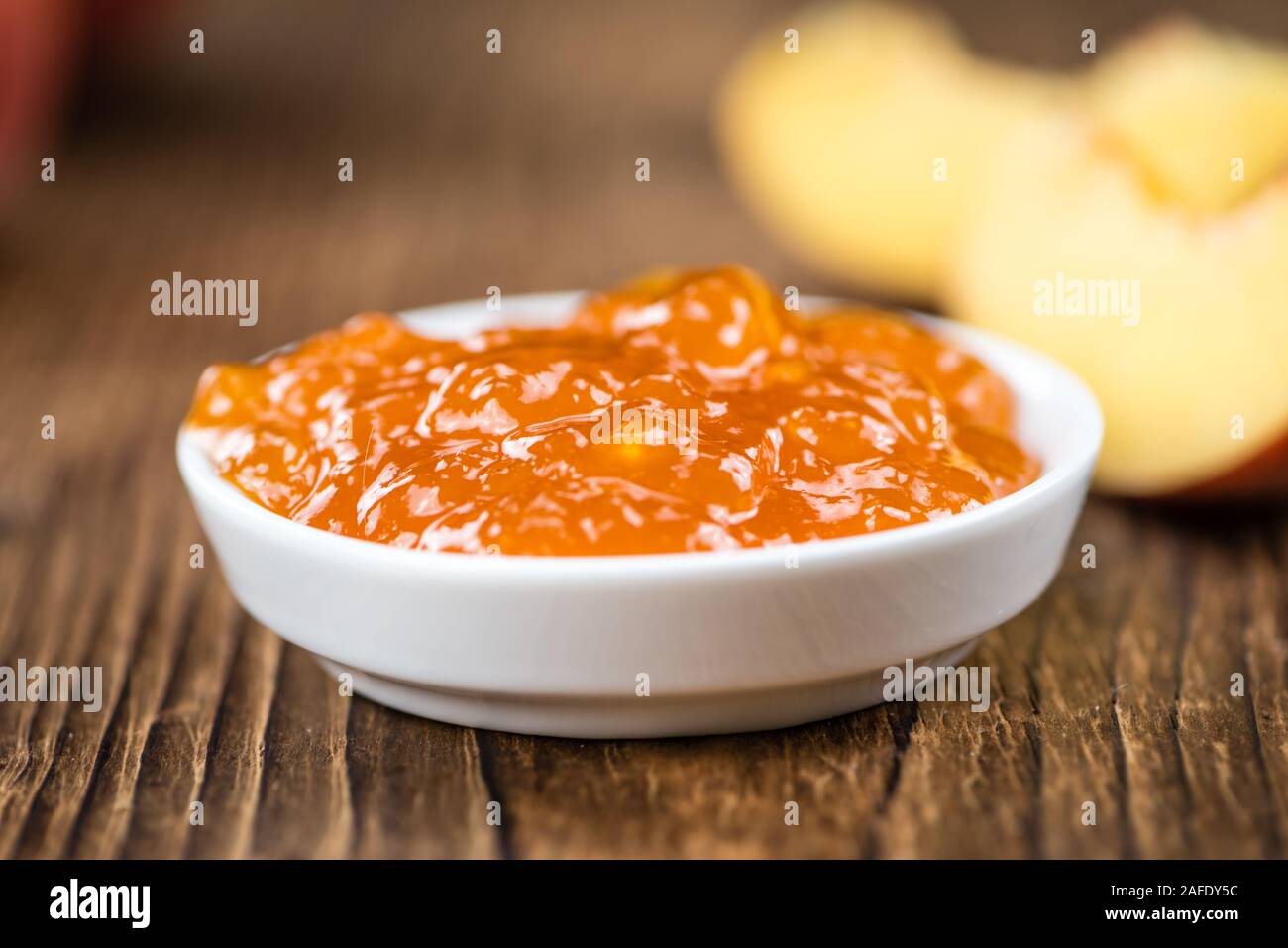 Confettura di pesche (messa a fuoco selettiva) su un vecchio tavolo di legno (close-up shot) Foto Stock