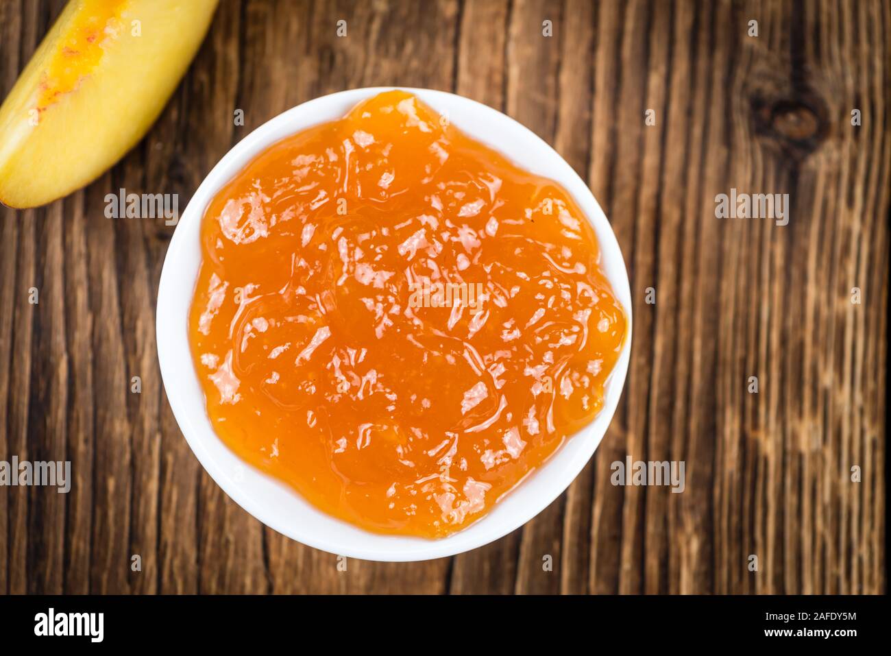 Tavolo in legno con confettura di pesche (messa a fuoco selettiva; close-up shot) Foto Stock