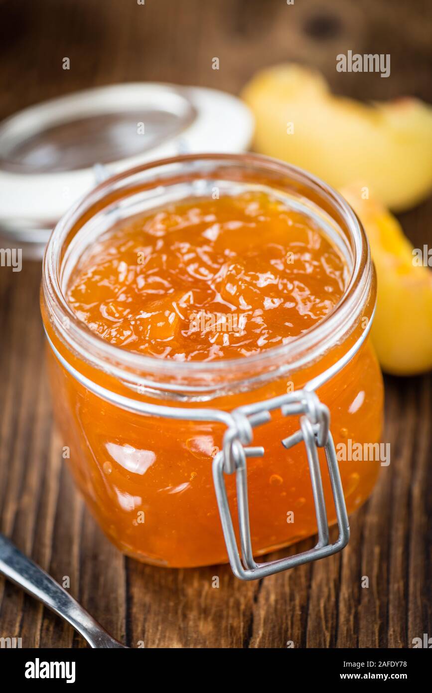 Fatta fresca confettura di pesche (close-up shot; messa a fuoco selettiva) su sfondo di legno Foto Stock