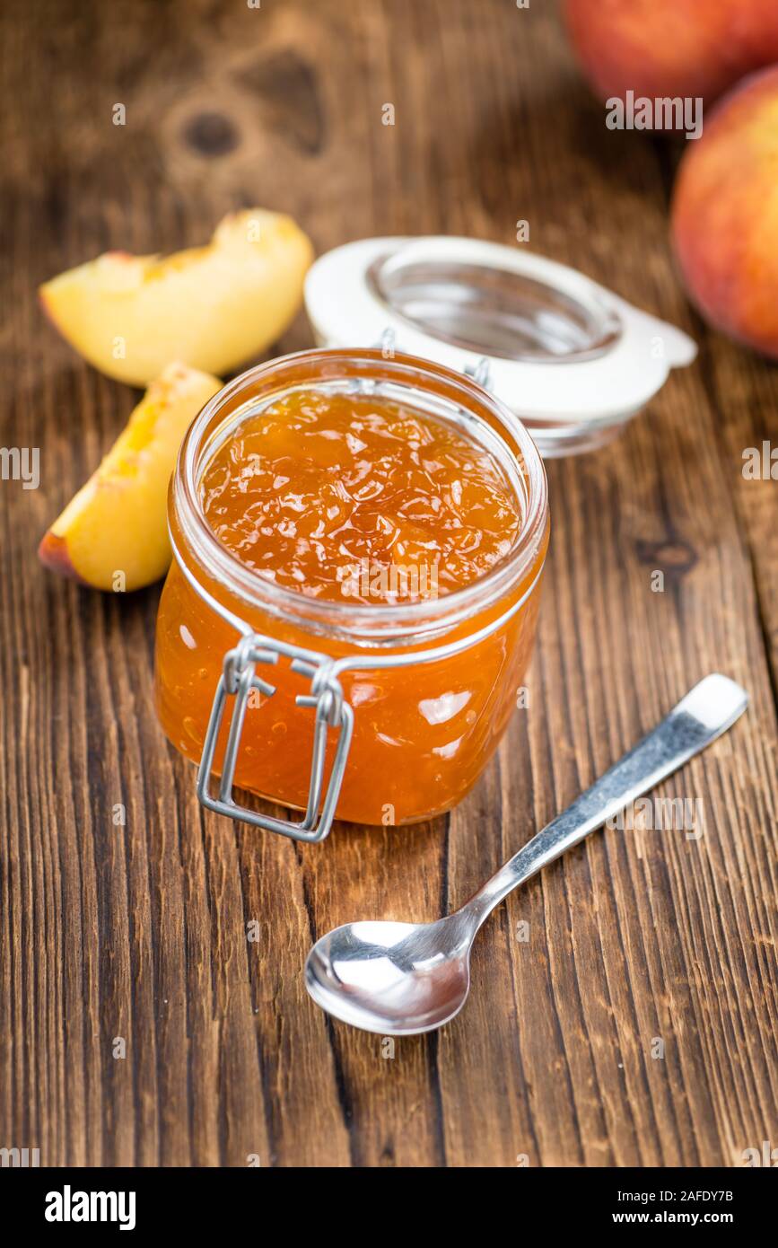 Tavolo in legno con confettura di pesche (messa a fuoco selettiva; close-up shot) Foto Stock