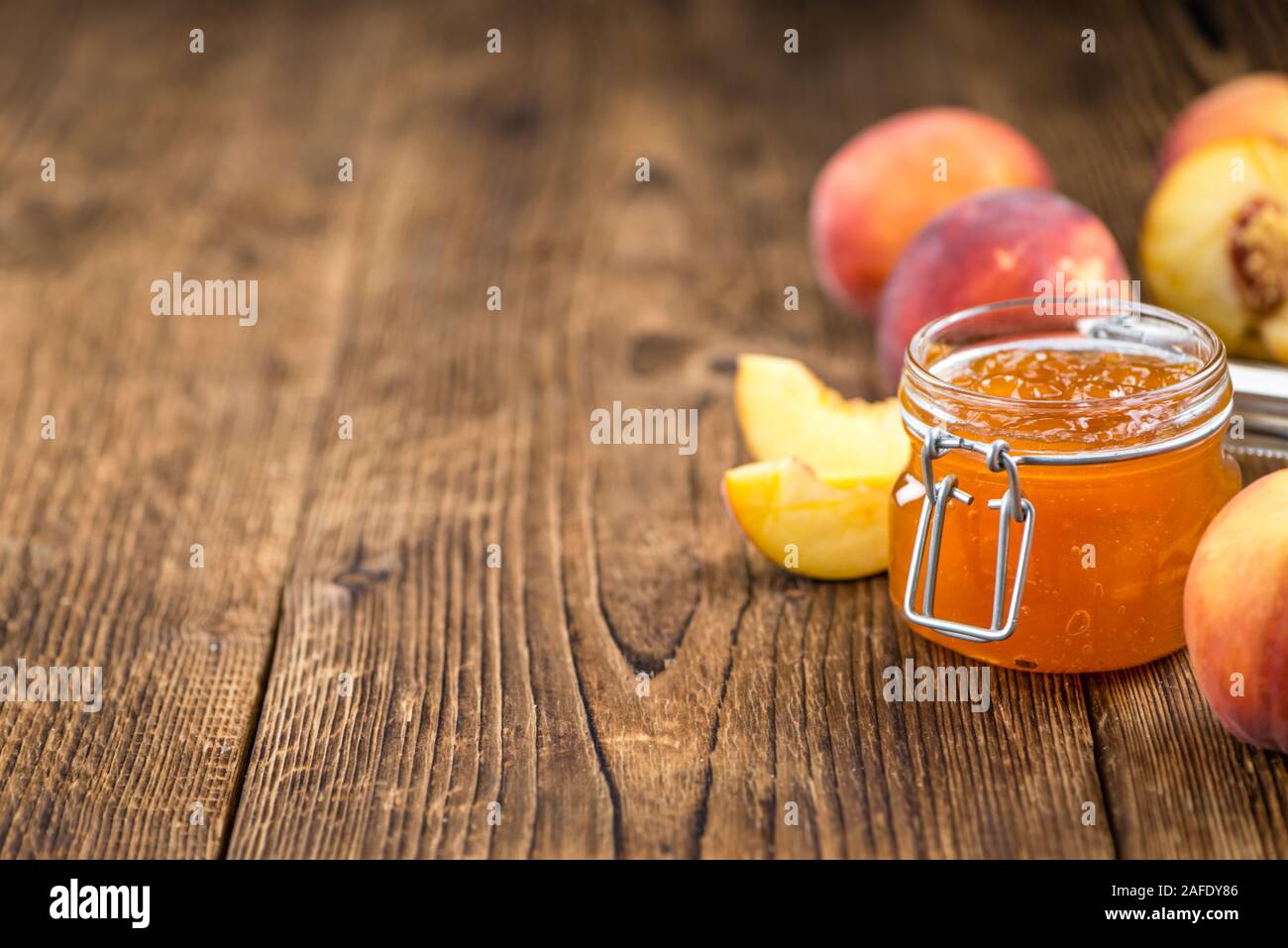 Confettura di pesche (messa a fuoco selettiva) su un vecchio tavolo di legno (close-up shot) Foto Stock