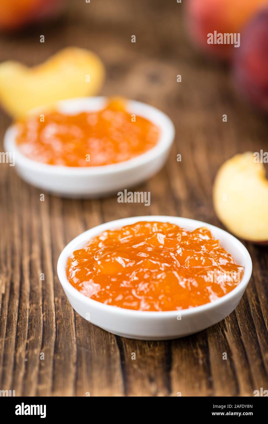 Confettura di pesche (messa a fuoco selettiva) su un vecchio tavolo di legno (close-up shot) Foto Stock