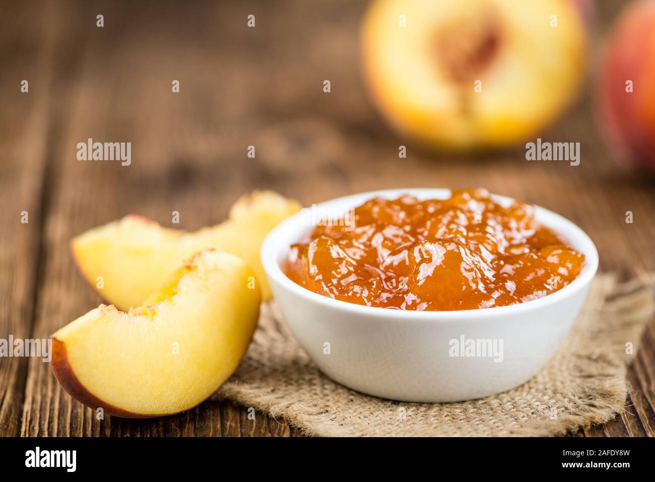Tavolo in legno con confettura di pesche (messa a fuoco selettiva; close-up shot) Foto Stock