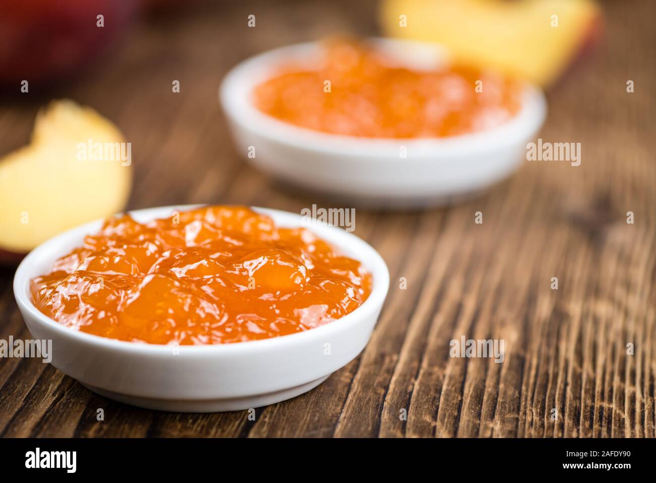 Tavolo in legno con confettura di pesche (messa a fuoco selettiva; close-up shot) Foto Stock