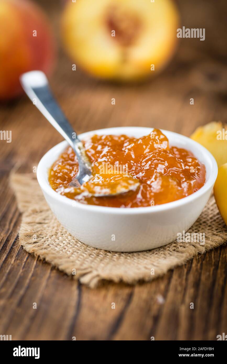 Confettura di pesche (messa a fuoco selettiva) su un vecchio tavolo di legno (close-up shot) Foto Stock