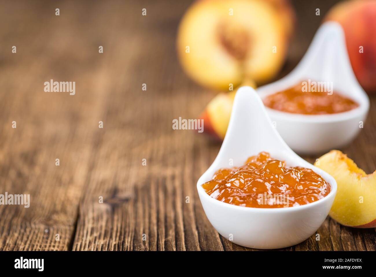Confettura di pesche (messa a fuoco selettiva) su un vecchio tavolo di legno (close-up shot) Foto Stock