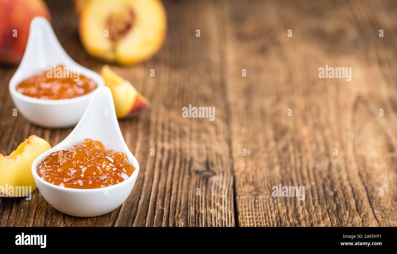 Fatta fresca confettura di pesche (close-up shot; messa a fuoco selettiva) su sfondo di legno Foto Stock