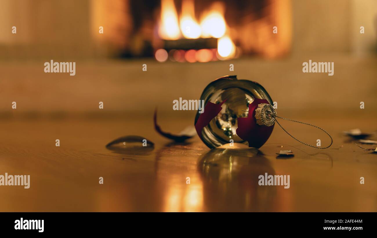 Pallina di natale rotto. Pallina di natale si è schiantato giù sul pavimento di legno. Vacanze di Natale sfondo, blur caminetto Foto Stock