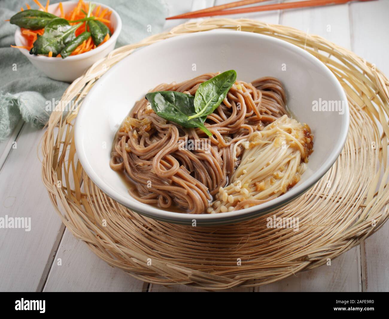 Zuppa giapponese con funghi Enoki, soba noodles, spinaci, la carota e la salsa di soia Foto Stock