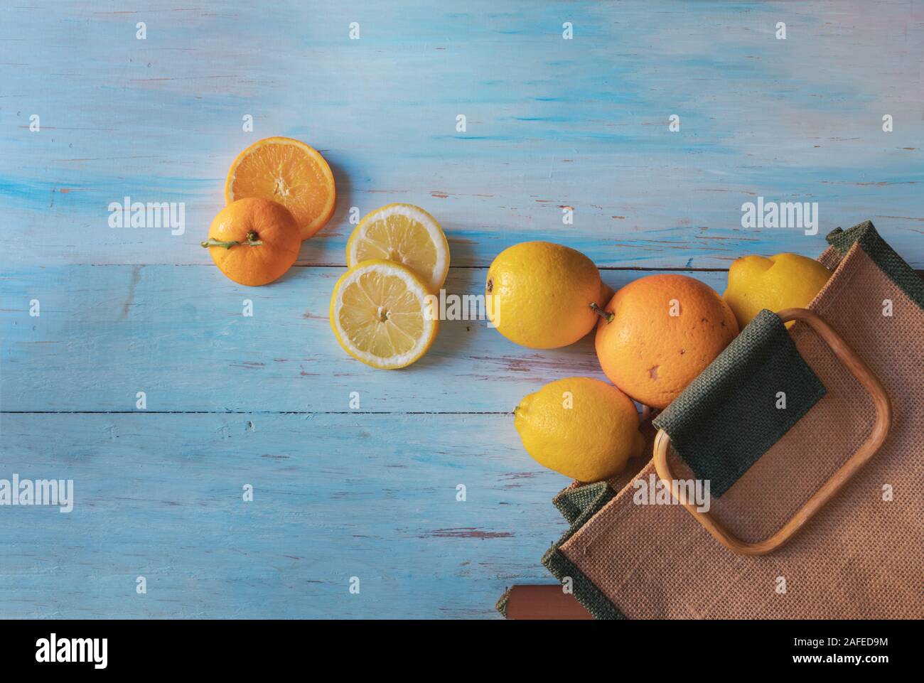 Ancora la vita di arance e di limoni provenienti al di fuori di un sacco su una luce sullo sfondo di legno Foto Stock