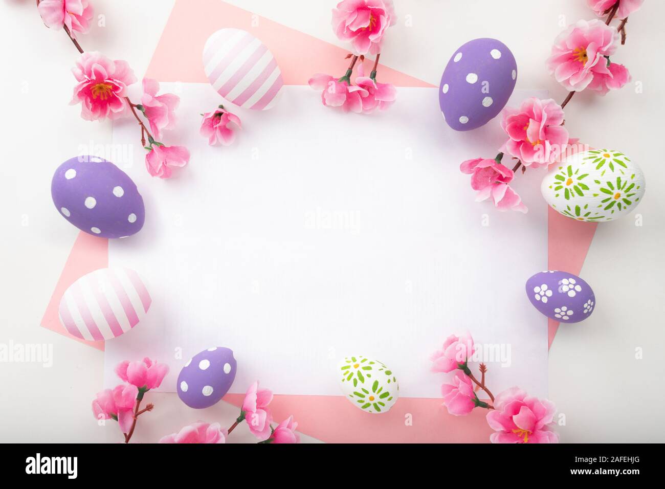 Telaio di pasqua di differente dimensione delle uova pasquali e carta colorata su uno sfondo bianco. Uova di Pasqua in vista superiore, piatto laici. Foto Stock