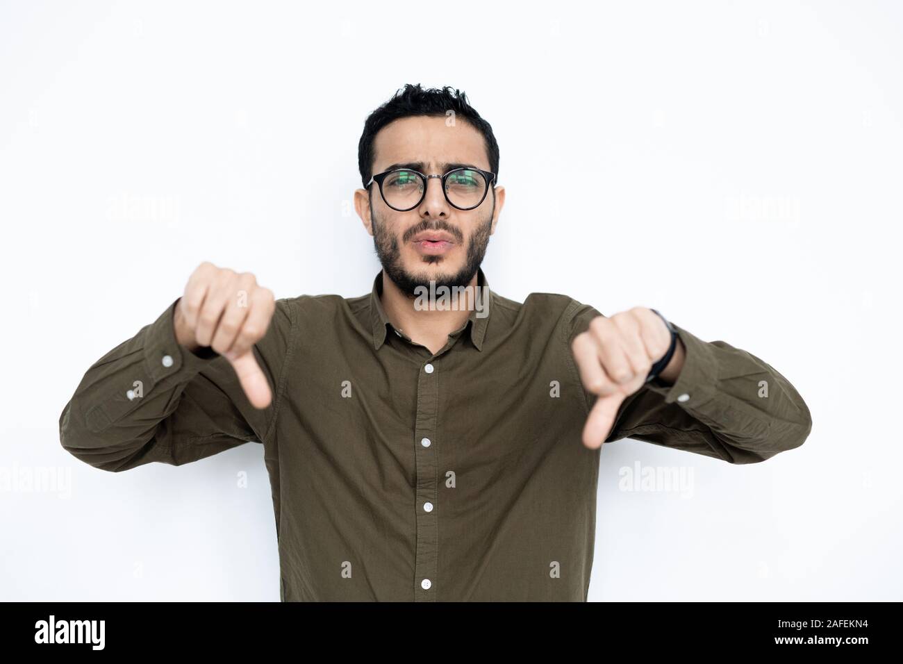 Giovane uomo in occhiali e informale che mostra antipatia gesto in isolamento Foto Stock