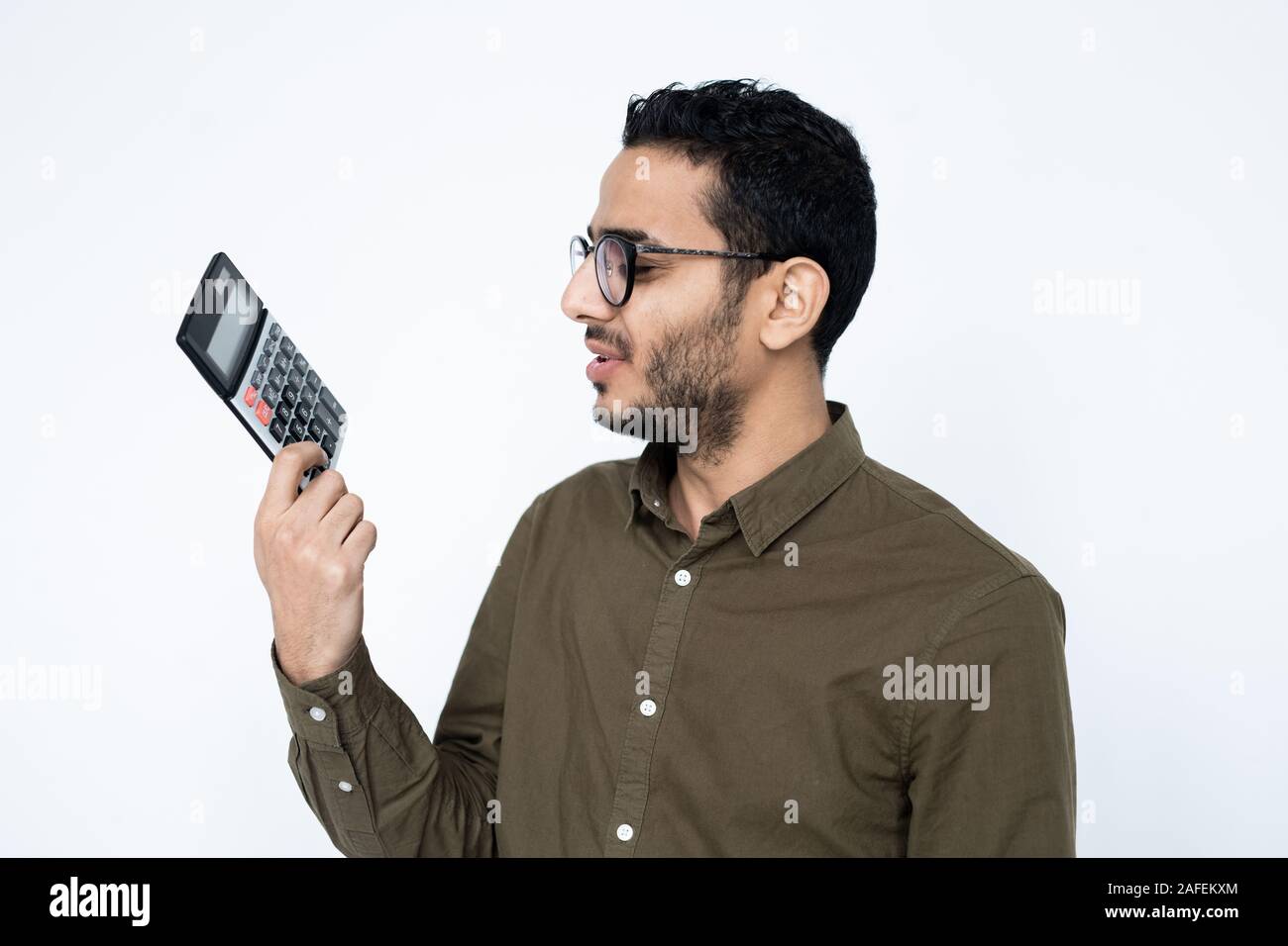 Giovane maschio commercialista o studente in occhiali guardando la calcolatrice in mano Foto Stock