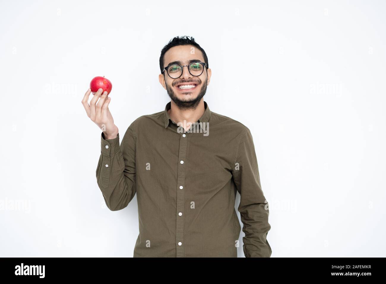 Felice giovane con sorriso toothy holding ripe rosso apple nel lato destro Foto Stock