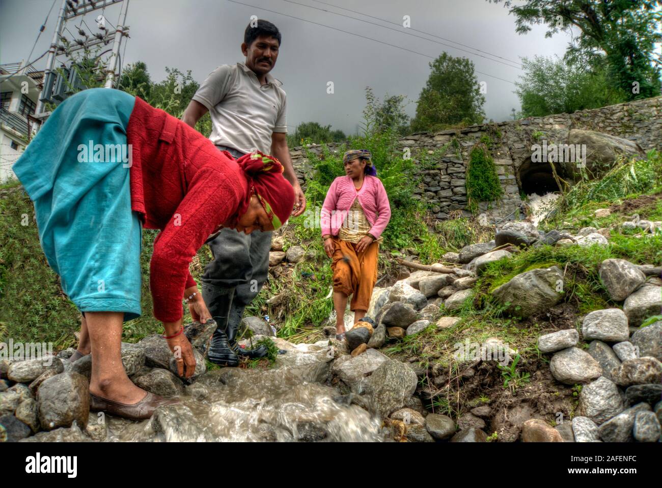 Vashisht, Himachal Pradesh, India: una donna Indiana che rimuove le pietre da un fiume dopo la pioggia Foto Stock