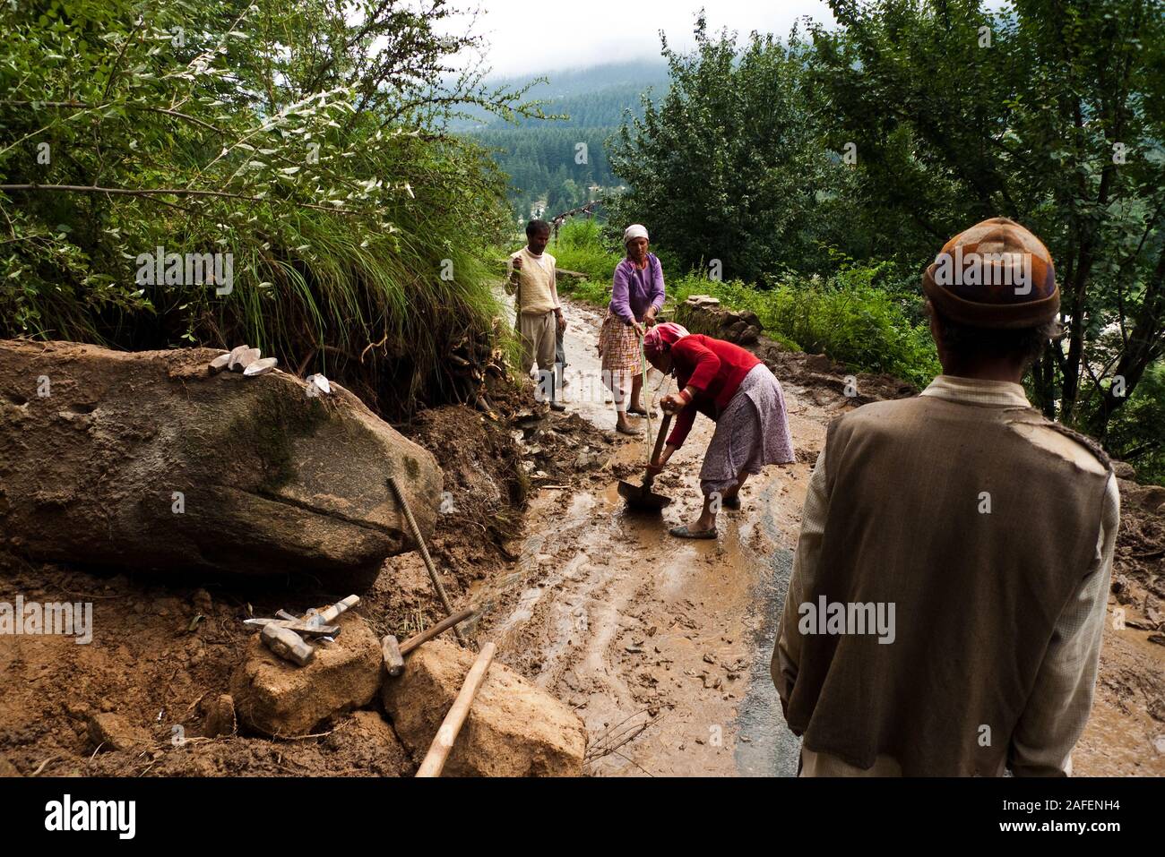 Vashisht, Himachal Pradesh, India: due donne pala fango da una strada Foto Stock