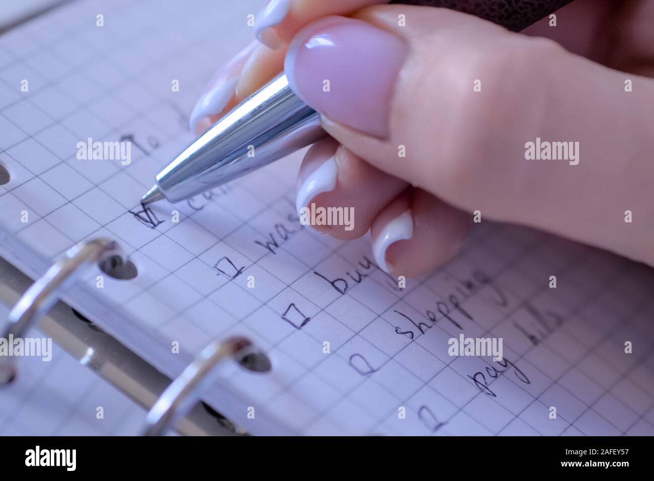 Donna mettendo il riferimento su caselle di controllo della Lista da fare in notebook - close up Foto Stock