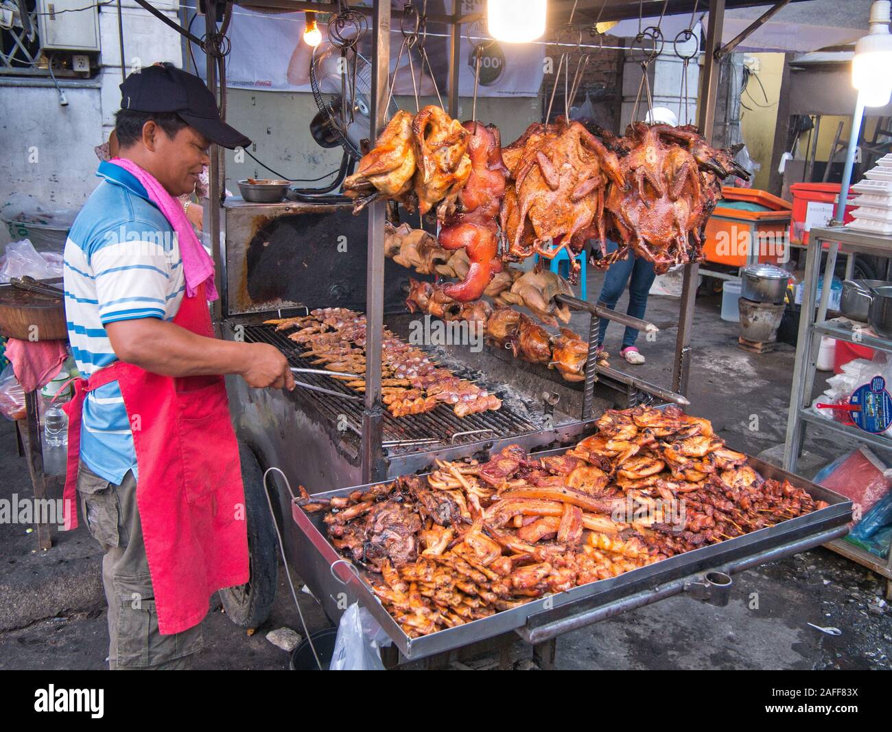 Un commerciante cuochi kebab spiedini di carne sui carboni ardenti di vendere come cucinati freschi, caldo cucina di strada in Phnom Penh Cambogia. Foto Stock