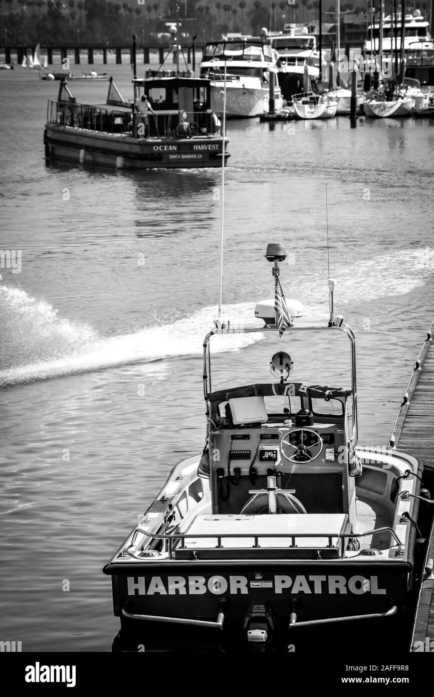 Vista posteriore del porto di Patrol in barca ormeggio presso il porto turistico di Santa Barbara con altre barche da pesca e barche a vela a Santa Barbara, CA, USA, in B&W. Foto Stock