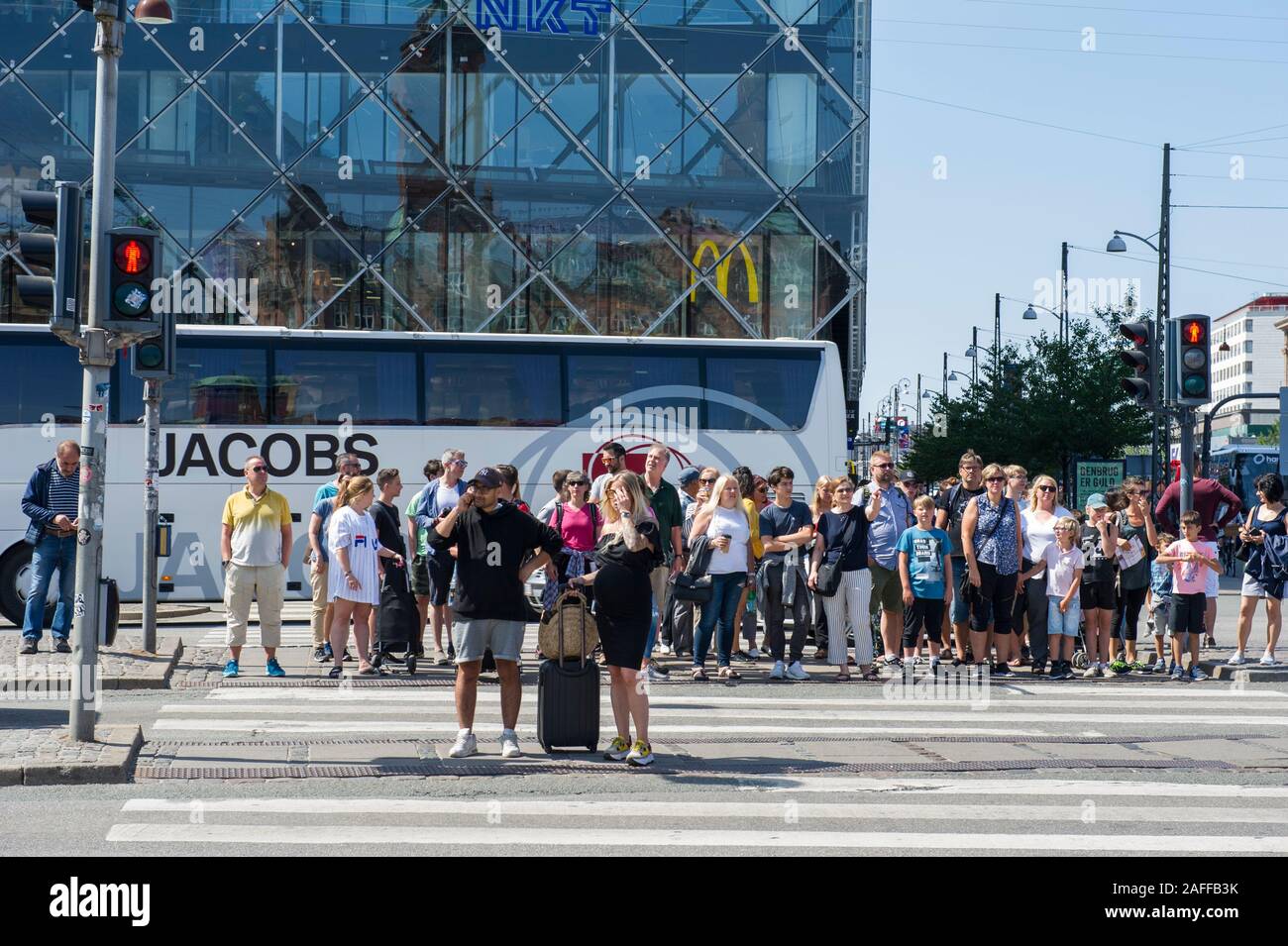 Un gruppo di pedoni in attesa di attraversare la strada in corrispondenza di un incrocio di Zebra di Copenhagen, Danimarca Foto Stock