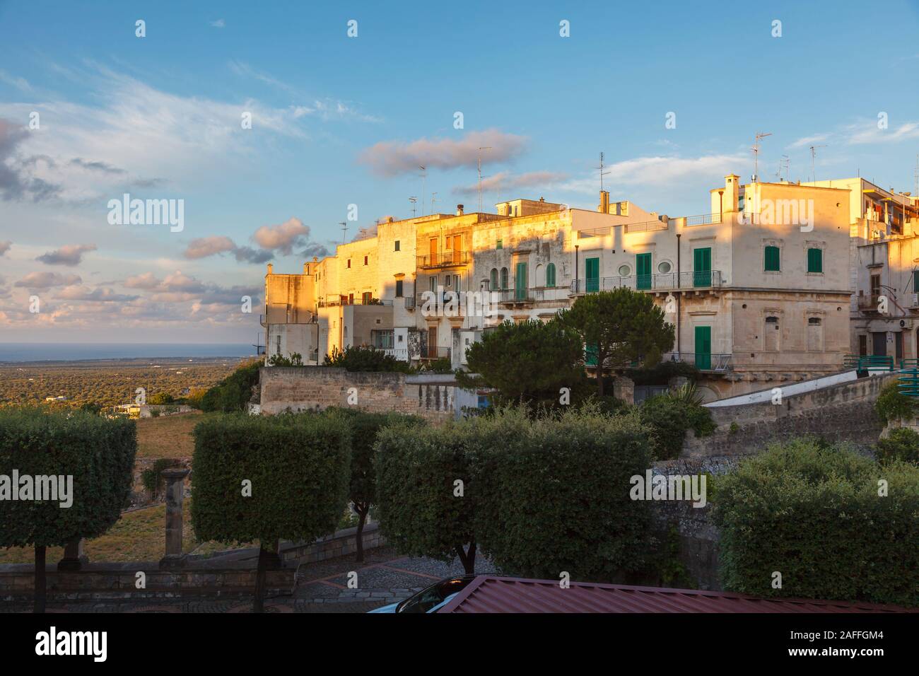 Gli edifici di vecchia costruzione nella storica città di collina di Ostuni nel distretto di Brindisi, puglia, Italia meridionale, illuminate da soft golden ora estate luce della sera Foto Stock