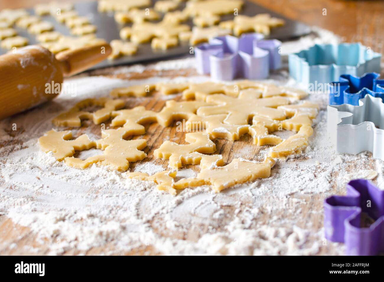 Zucchero arrotolata pasta biscotto con il mattarello e cookie cutters sfocati in background. Messa a fuoco selettiva. N. persone. Foto Stock