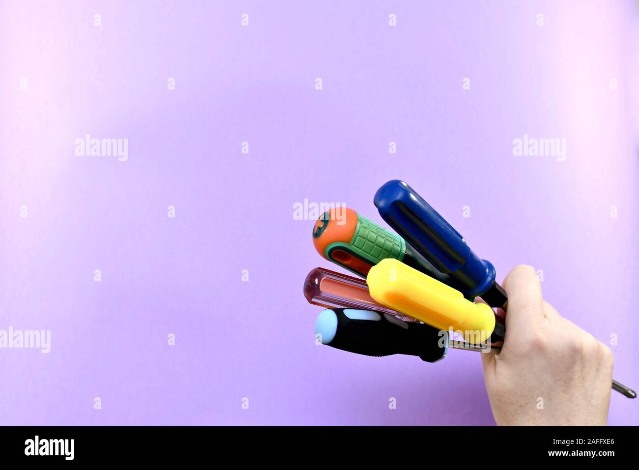 Un mazzetto di differenti nel colore e nella forma cacciaviti, serrato nel pugno della mano femminile. Foto Stock