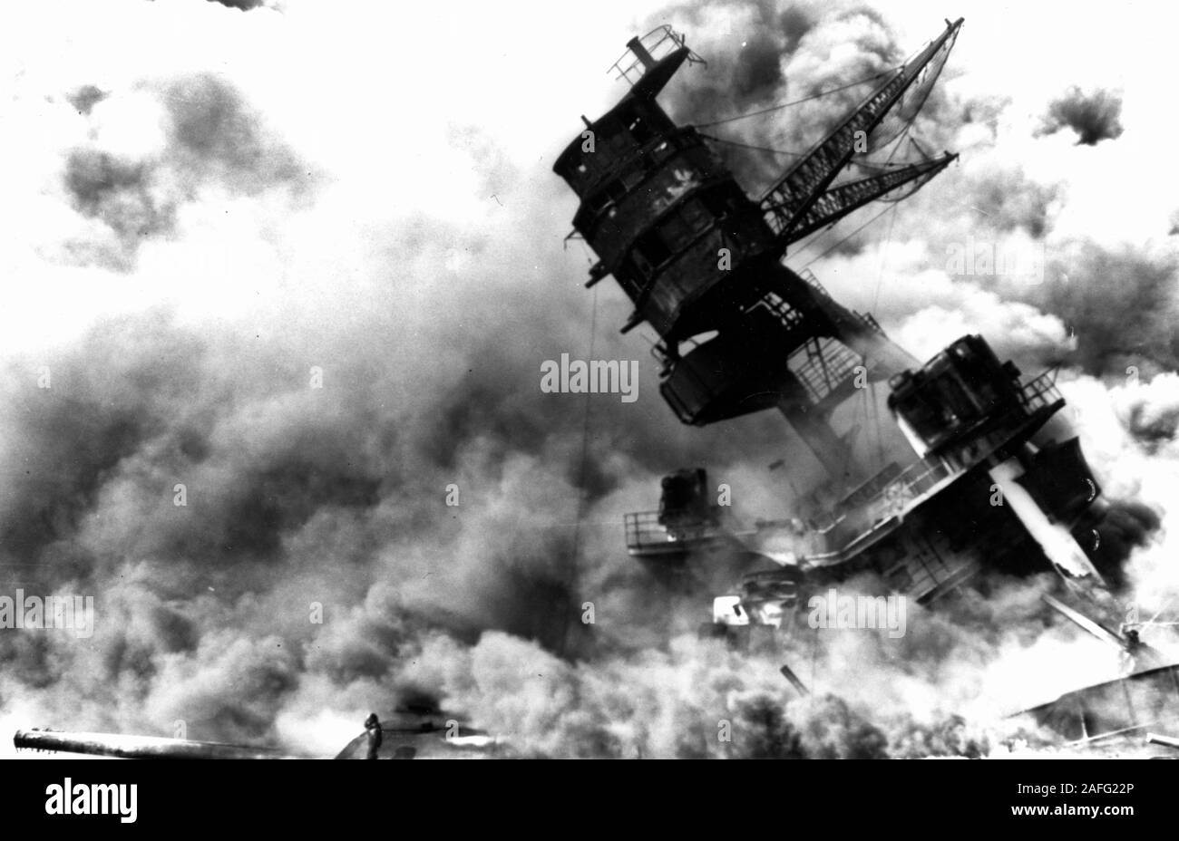 Attacco di Pearl Harbor, 7 Dicembre 1941 - La sovrastruttura in avanti e il numero due 14/45 triple torretta mitragliatrice dei sunken USS Arizona (BB-39), ardente dopo il raid giapponese, 7 dicembre 1941. Il foremast è pendente a seguito del crollo della struttura di scafo al di sotto della sua gamba anteriore, dopo l'esplosione della nave di avanti riviste. Foto Stock