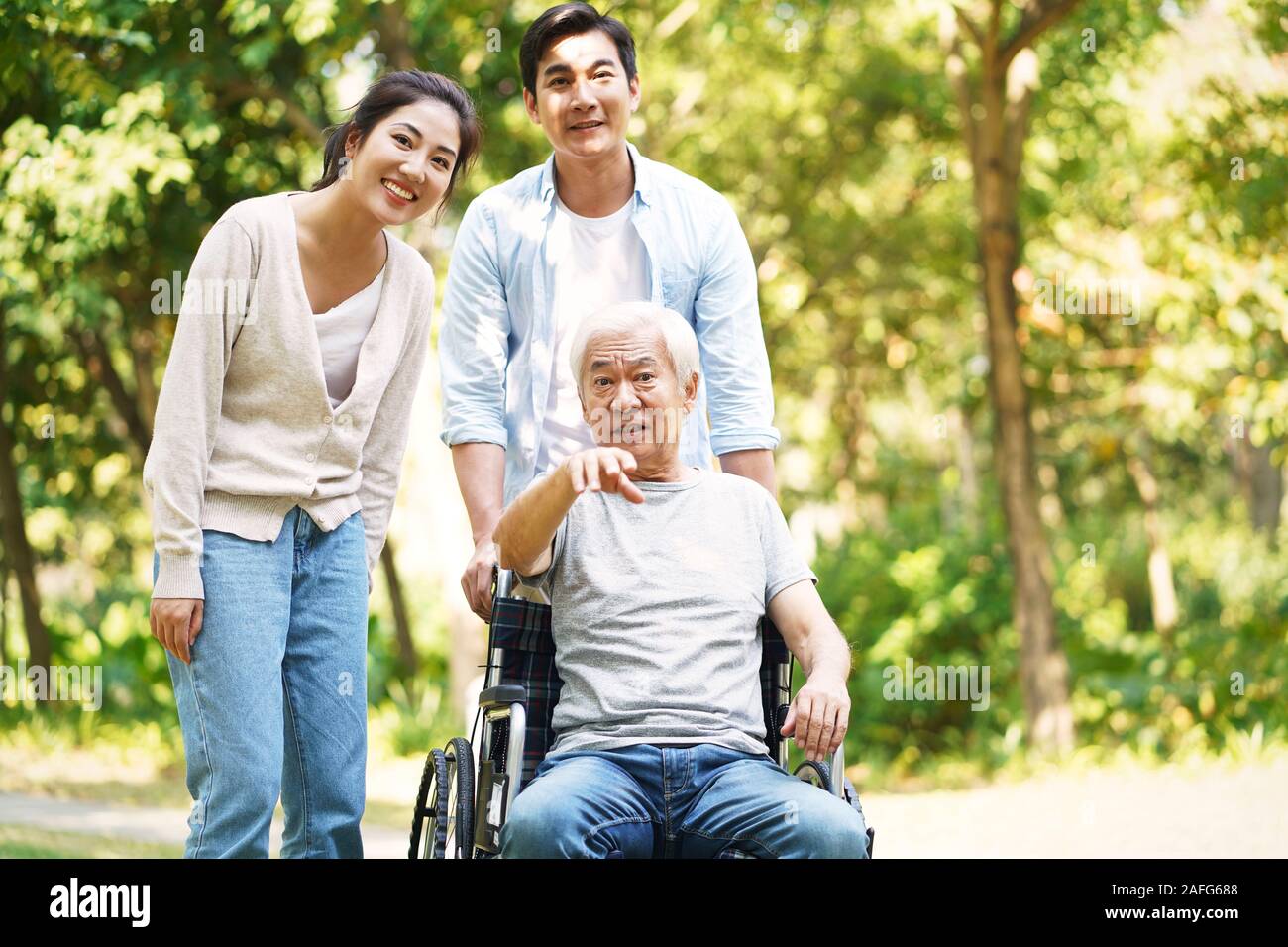 Giovani asiatici giovane e sedia a rotelle padre legato di relax all'aperto nel parco Foto Stock