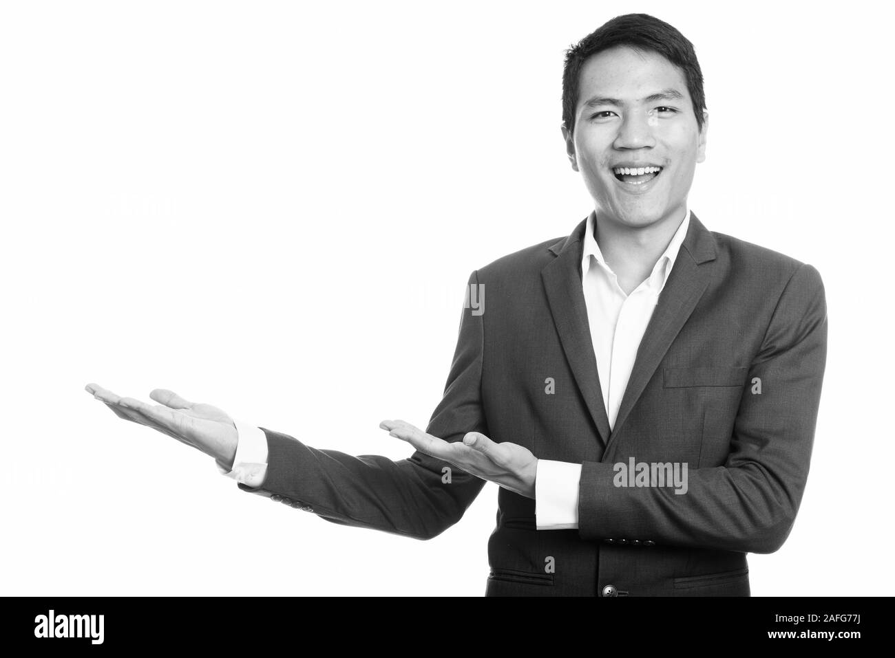 Giovani asiatici happy businessman sorridente e mostrando qualcosa di Foto Stock