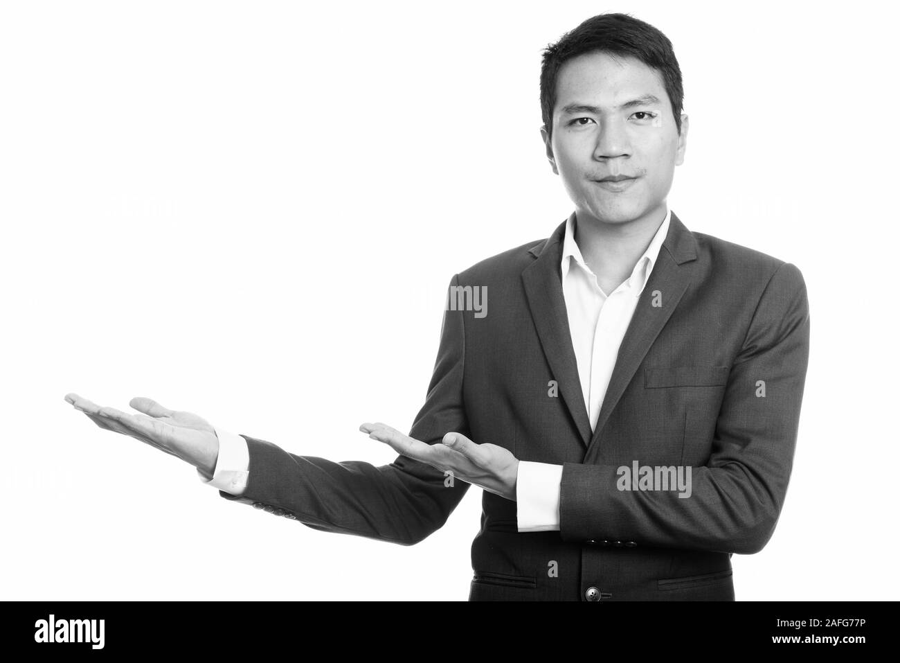 Studio shot del giovane imprenditore asiatico che mostra qualcosa Foto Stock