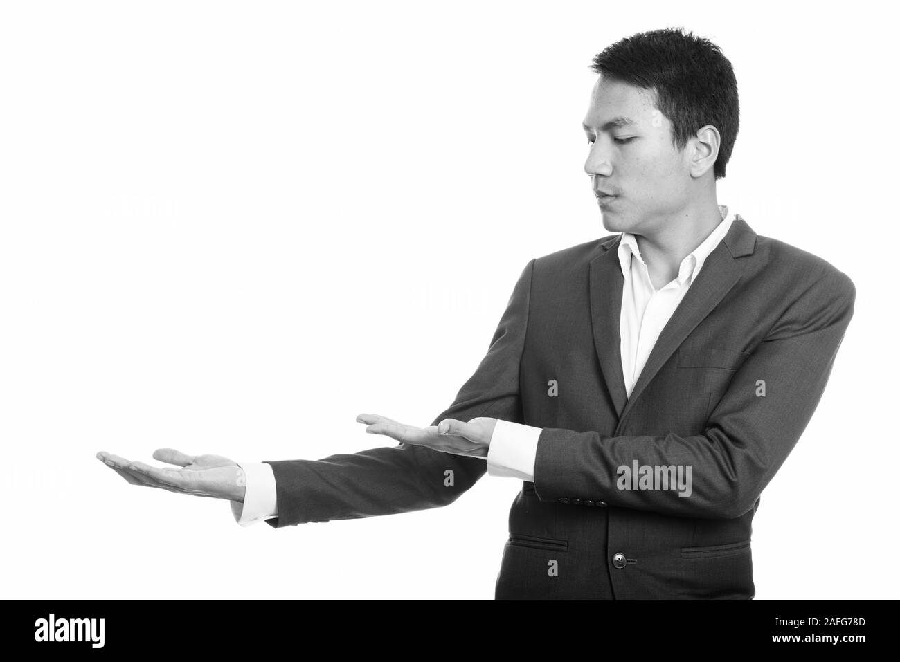 Studio shot del giovane imprenditore asiatico che mostra qualcosa Foto Stock