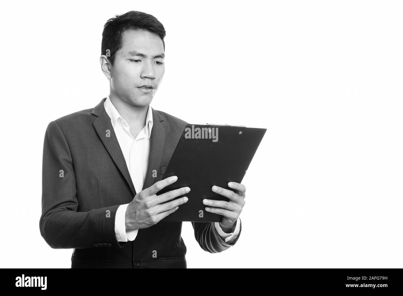 Studio shot del giovane imprenditore asiatici lettura sulla clipboard Foto Stock