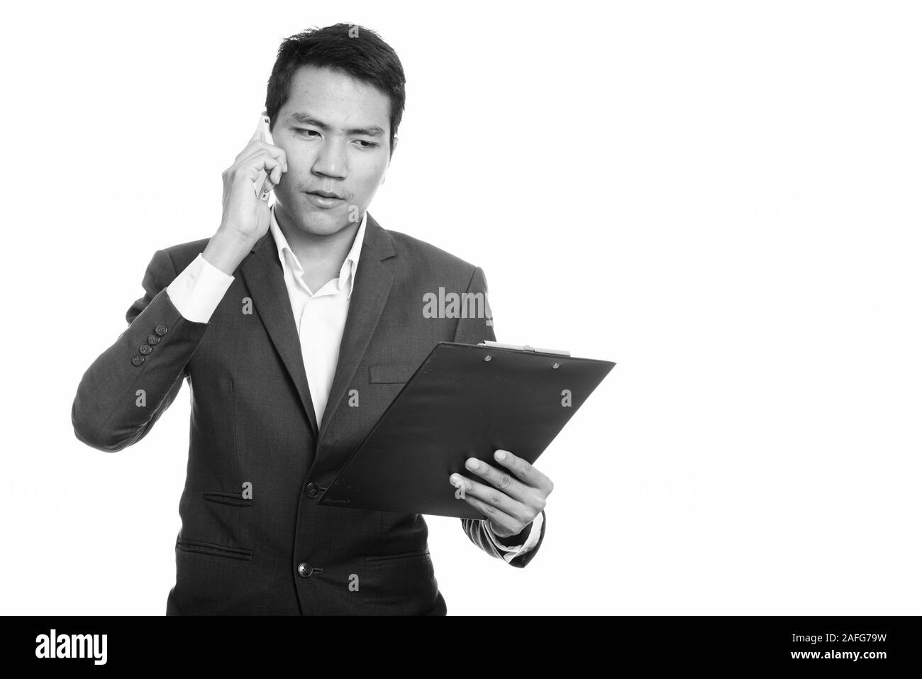 Giovane imprenditore asiatici lettura su appunti mentre parlano al telefono cellulare Foto Stock