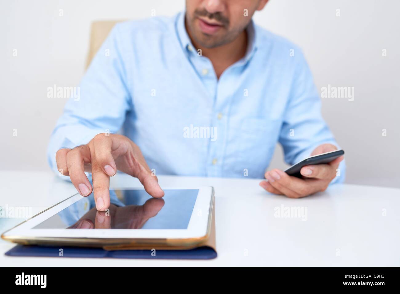 Il giovane imprenditore zoom indietro su immagine digitale compressa quando si lavora su tablet a scrivania da ufficio Foto Stock