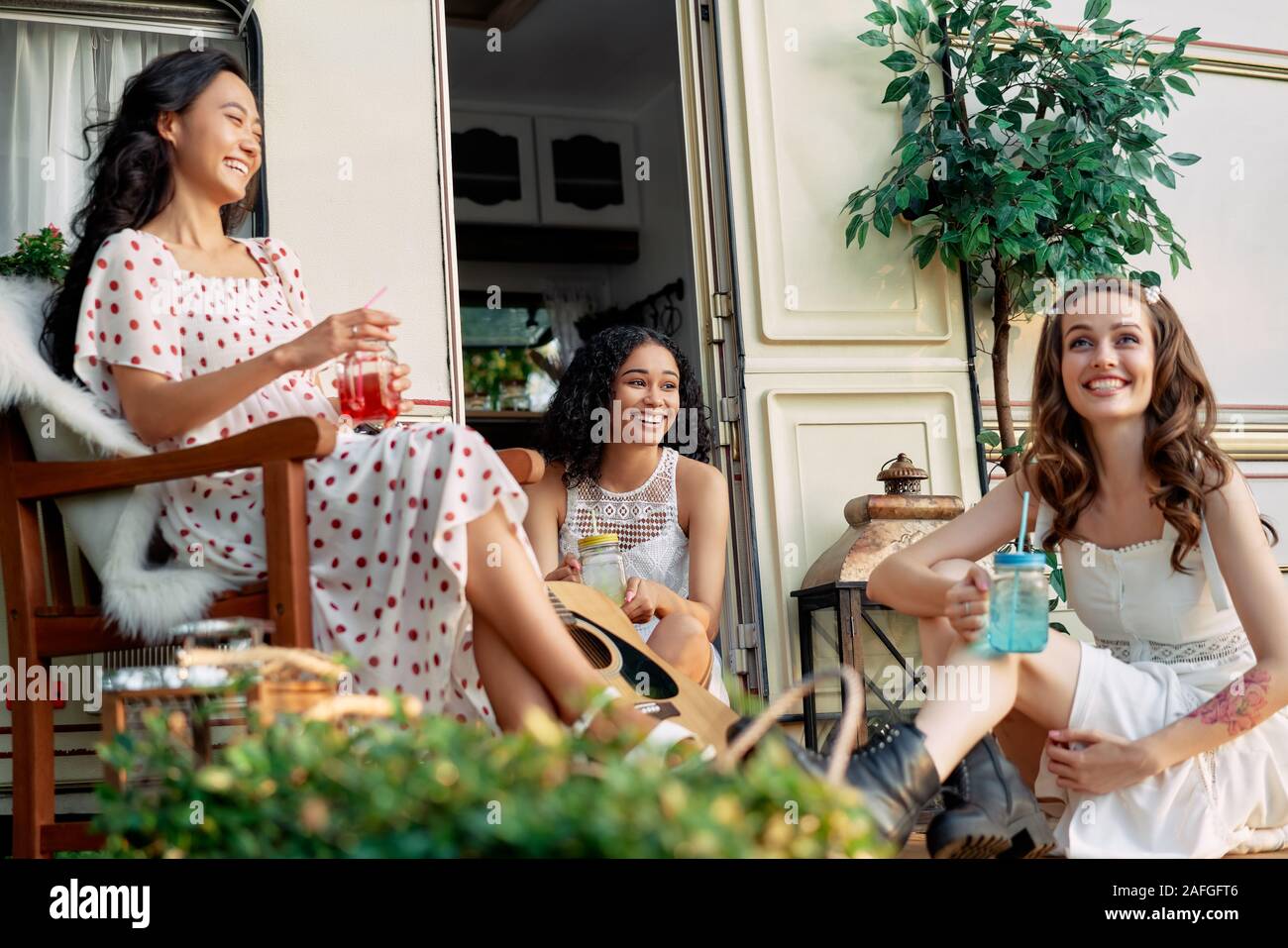 Giovani felici donne divertirsi insieme godere di pic-nic nei pressi del loro camper durante il viaggio estivo. multi etnico bellezza femminile Nozione Foto Stock