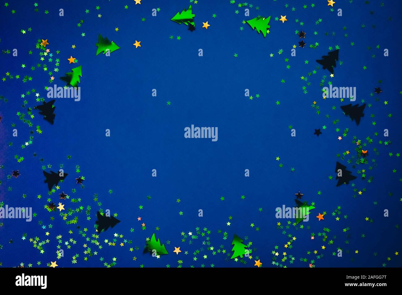 Telaio di Natale composizione con golden a forma di stella di paillettes e alberi di pino di colore blu su sfondo olografica. Celebrazione il concetto di preparazione. Selective Foto Stock