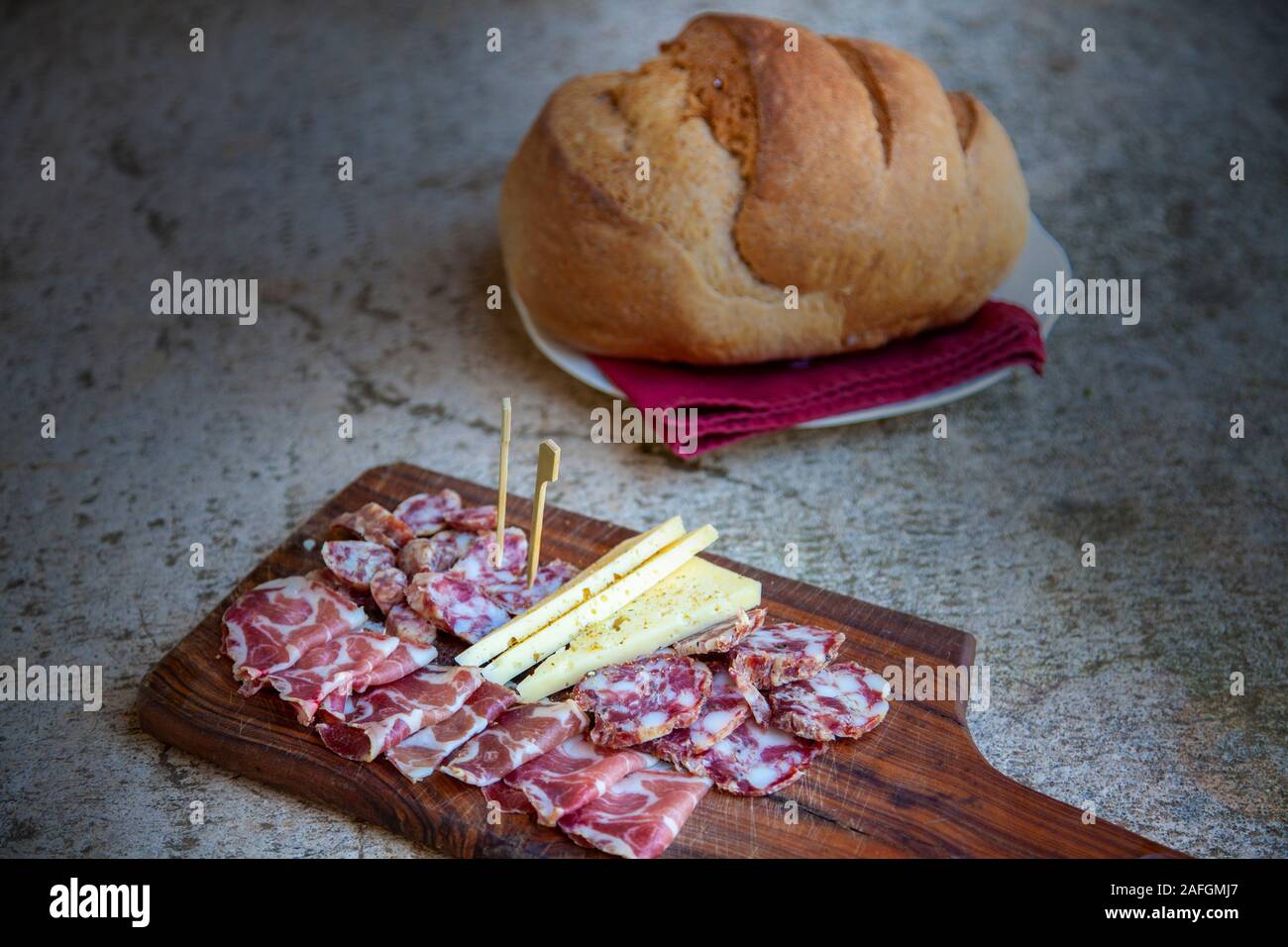 Carsico tipico affettato sul piatto di prosciutto casalingo, prosciutto, salame e formaggio cosparso con spezie sul tavolo di pietra Foto Stock