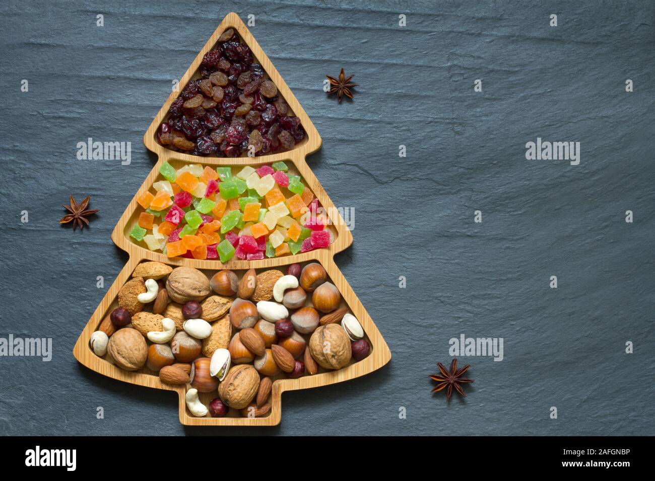 Albero di natale con noci e frutta secca su sfondo scuro Foto Stock