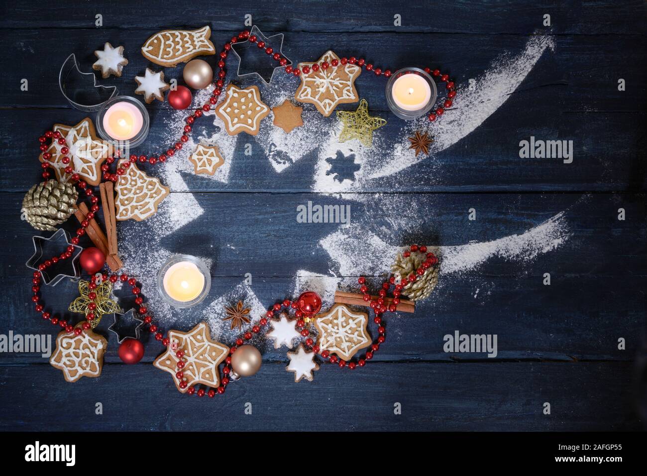 Stella Cadente forma da zucchero a velo, decorazione di Natale, gingerbread cookie e candele accese su un blu scuro dello sfondo in legno, ad alto angolo di visione Foto Stock