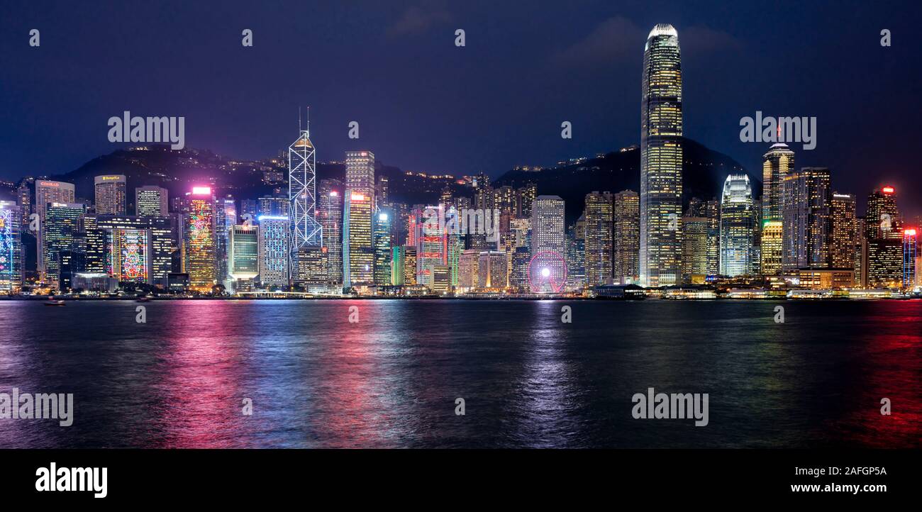 Panorama di alto-aumento edifici sul lungomare illuminato di notte. Hong Kong, Cina. Foto Stock