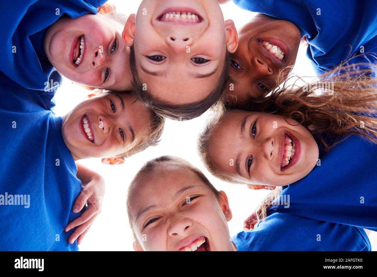 Basso angolo vista guardando in volti di bambini In Huddle sulla giornata di sport Foto Stock