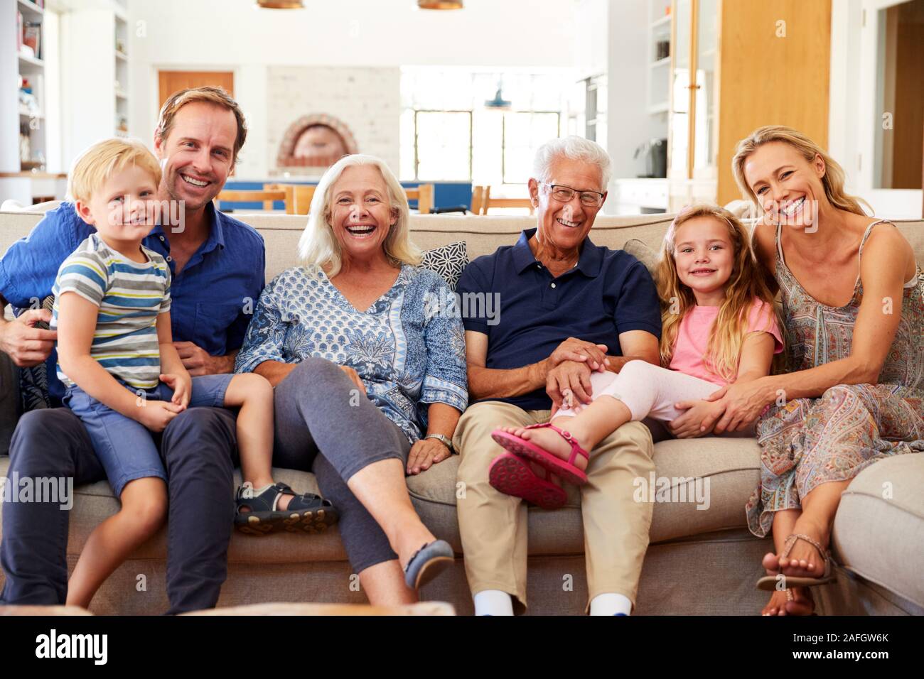 Ritratto di famiglia Multi-Generation seduti sul divano di casa sorridente in telecamera Foto Stock