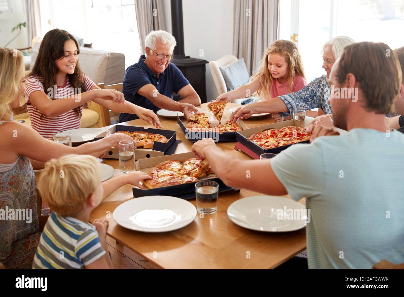 Multi generazione Famiglia seduti a tavola a mangiare la pizza da asporto insieme Foto Stock