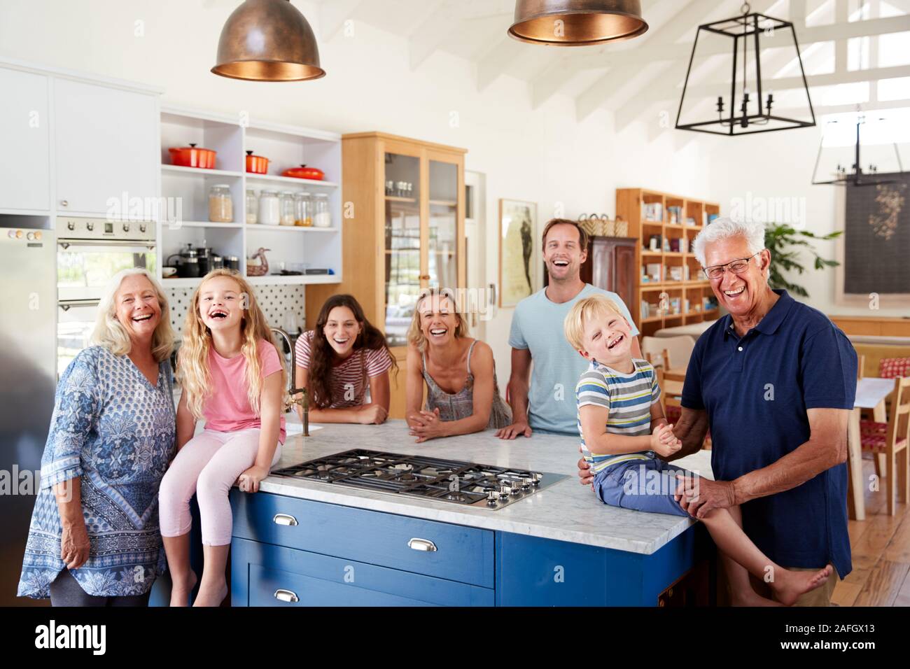 Ritratto di Multi generazione permanente di famiglia intorno all Isola della cucina insieme Foto Stock