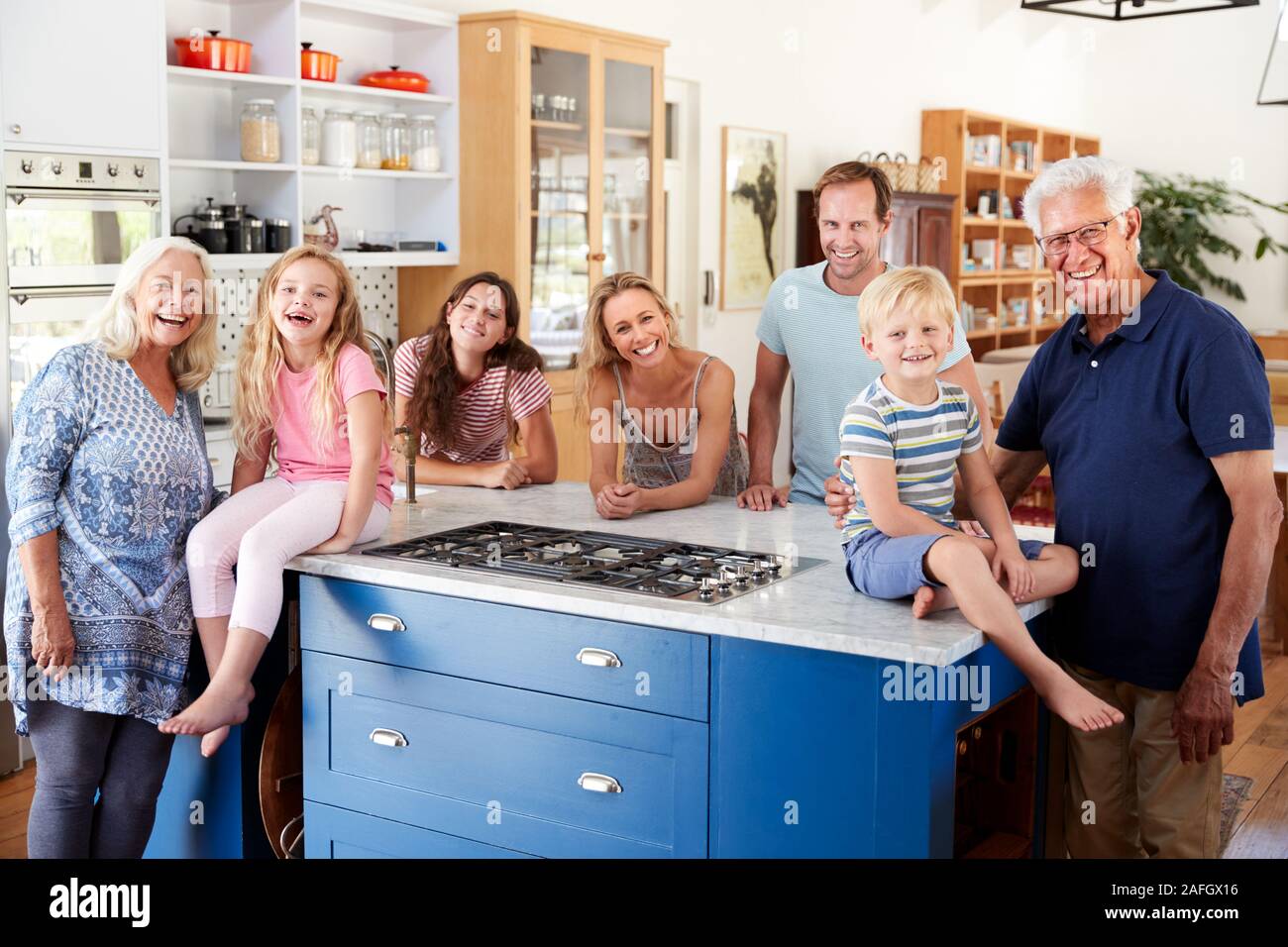 Ritratto di Multi generazione permanente di famiglia intorno all Isola della cucina insieme Foto Stock