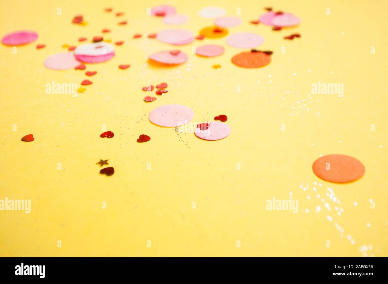 Coriandoli colorati, brilla luminoso su sfondo giallo. Sfondo di festa. Foto Stock