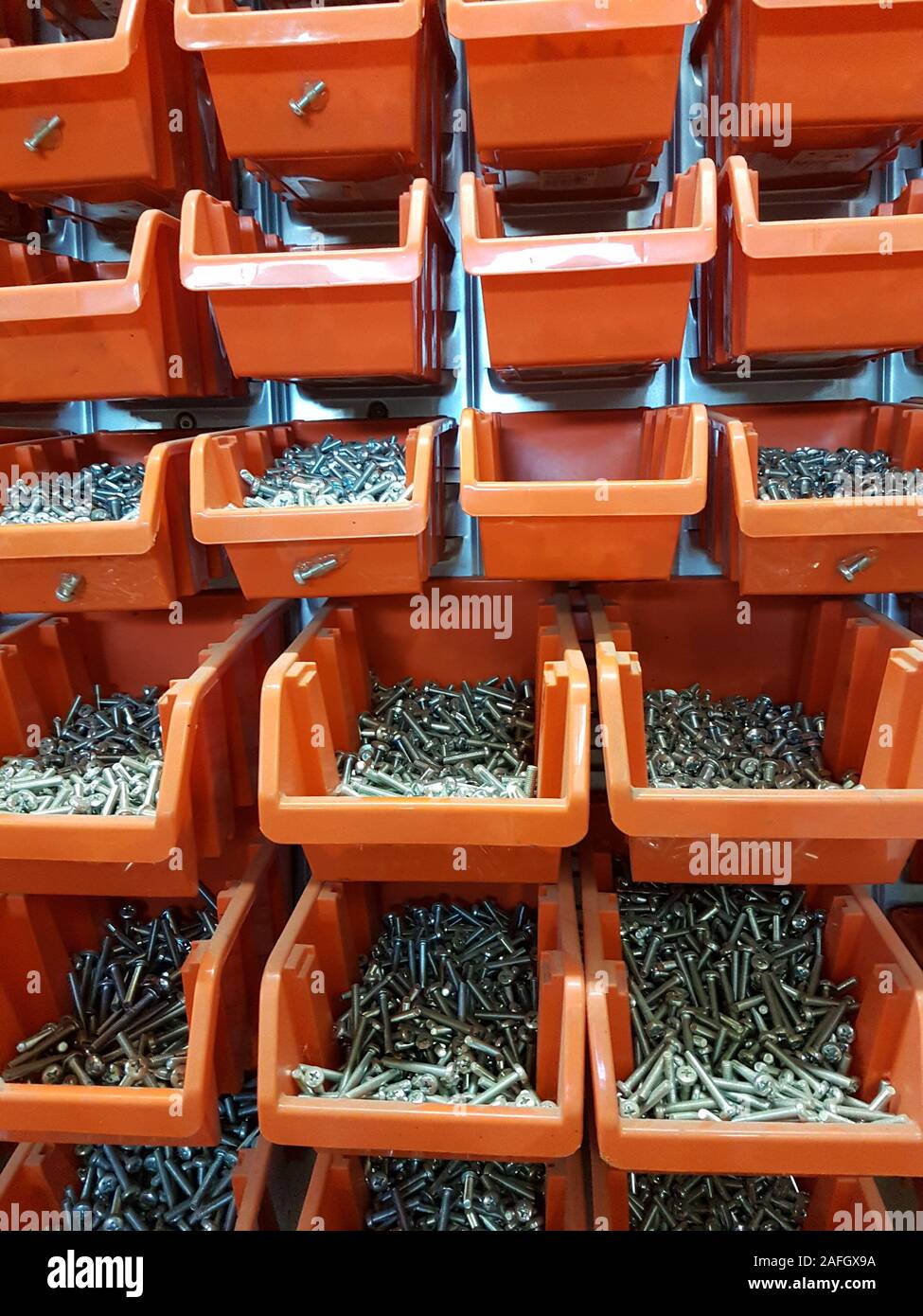Avvitare le scatole di stoccaggio arancioni in un'officina Foto Stock