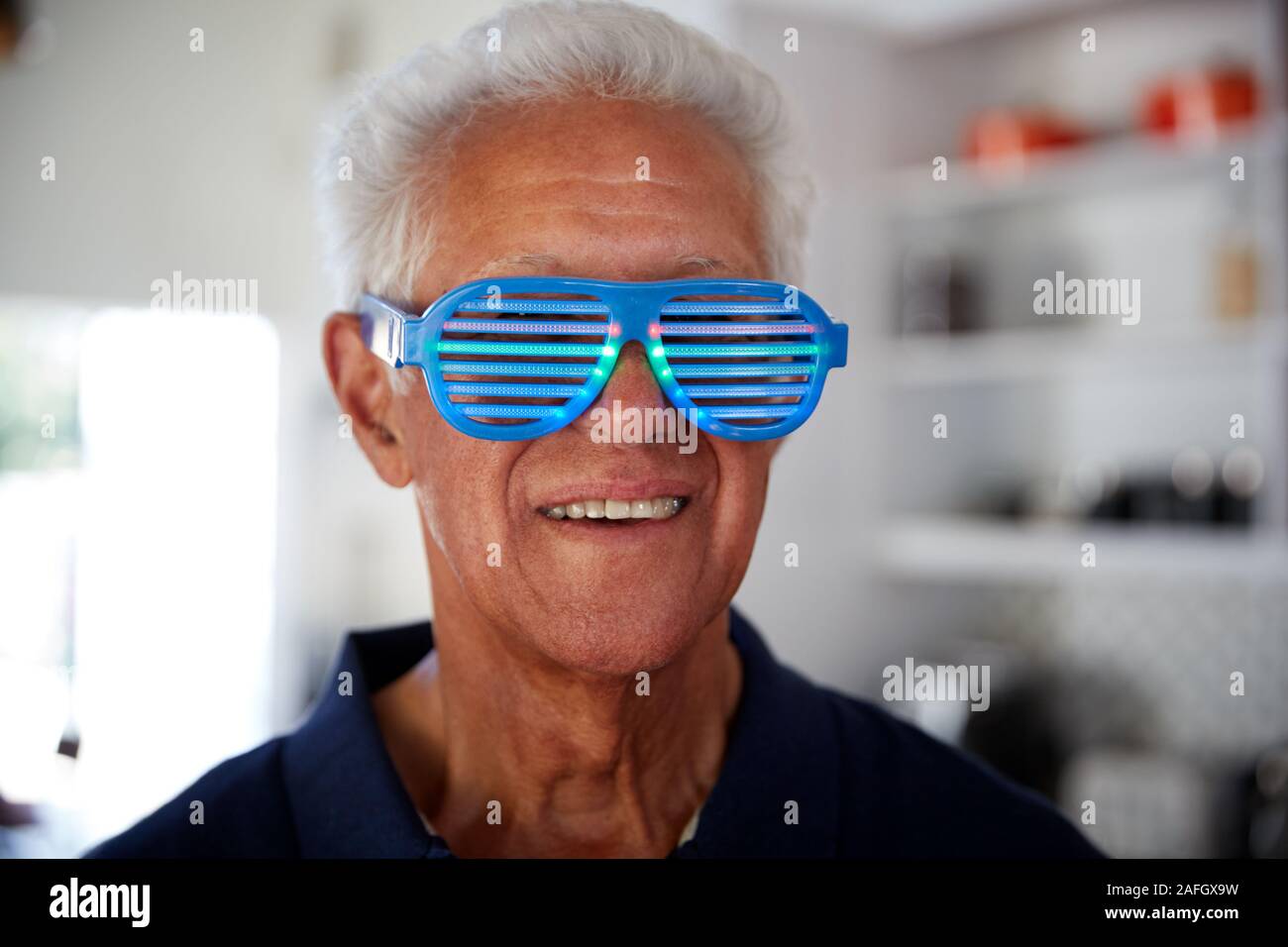 Senior Man a Home Novità che indossa gli occhiali di partito Foto Stock