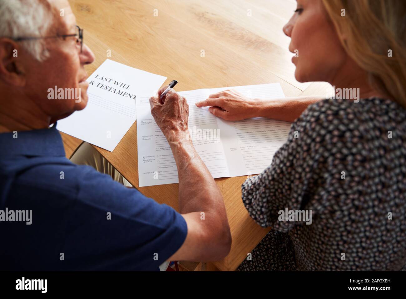 La donna aiuta l uomo Senior per completare l'ultima volontà e testamento a casa Foto Stock